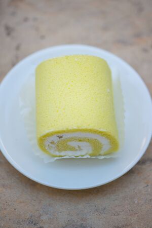 Sponge cake cream roll on white dish show bakery backgroundの写真素材