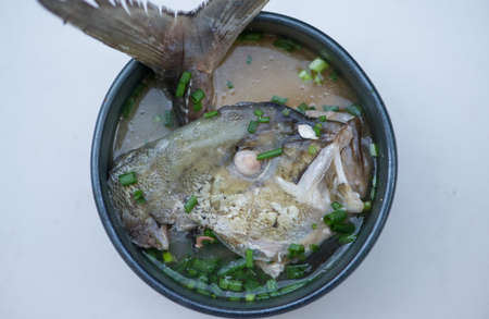 Miso soup with head fish in black dishの写真素材