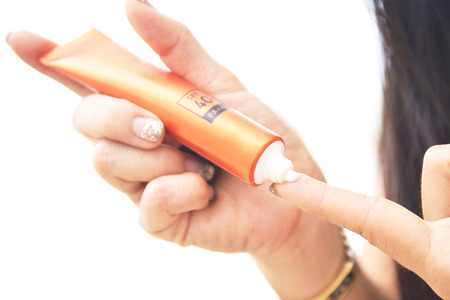 female hands with sunscreen cream uv protection on white background