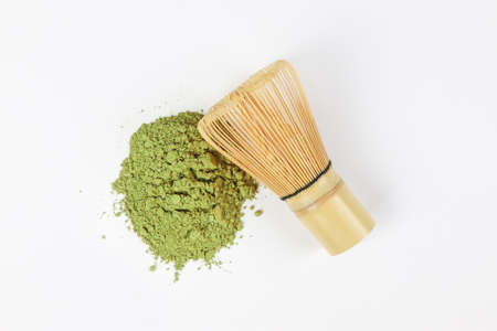 Matcha, green tea powder and bamboo whisk on white background