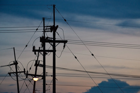 Silhouette of electric poles and power lines with colorful twilight sky backgroundの写真素材