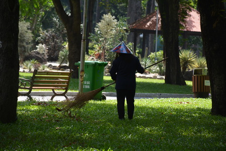 Worker sweeping dried leaves in a parkのeditorial素材