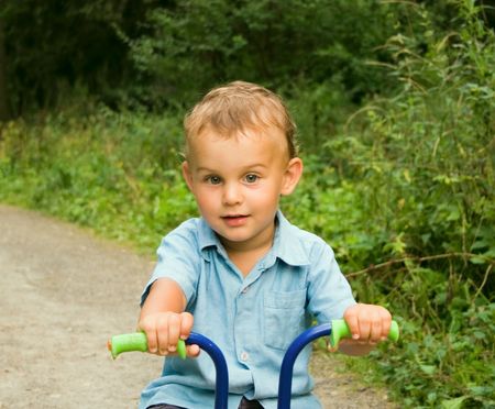 Boy riding bicycle in forestの写真素材