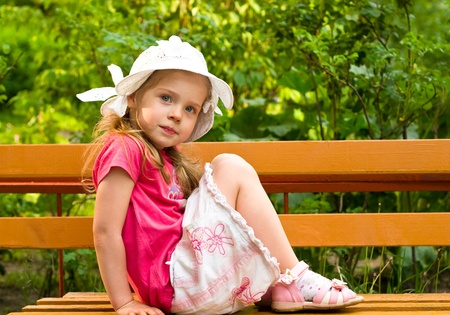 little girl sitting on the bench in parkの写真素材