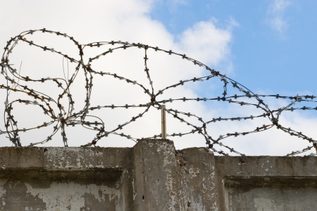 Stone wall with barbed wire against blue skyの写真素材