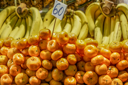 Tamgerines pile on a fruit stall under Incandescent lightの写真素材