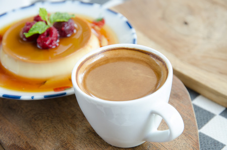 Espresso coffee in a white cup with caramel custard  on the table.の写真素材