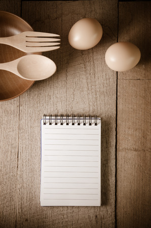 Open cookbook and kitchenware on wooden table backgroundの写真素材
