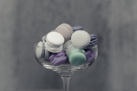 colorful macaroons in clear glass display on wooden tableの写真素材