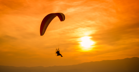 Silhouette paraglider on sunset sky backgroundの写真素材