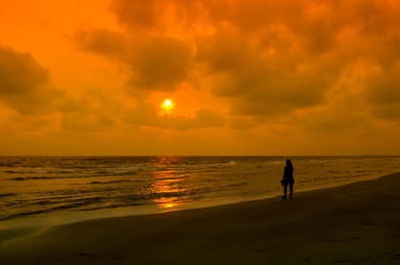 Silhouette woman walking on the beach on sunset time