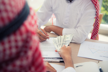 Businessman Arabian signing contract and exchange money together.