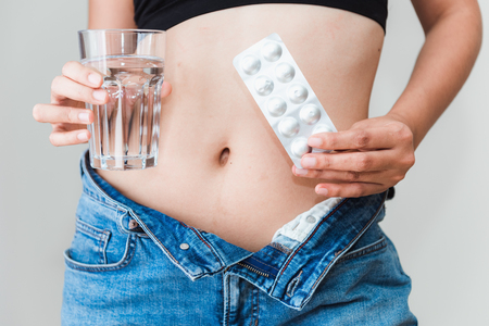 Portrait of young woman showing diet pills with a glass of water., Healthcare and medical concept.の写真素材