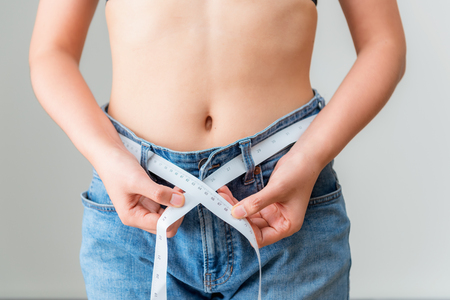 Portrait of hands measuring waist with a tape. Healthy and diet conceptの写真素材