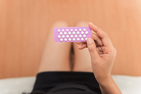 Asian woman holding contraceptive pills in the bed room., Health and medical conceptの写真素材