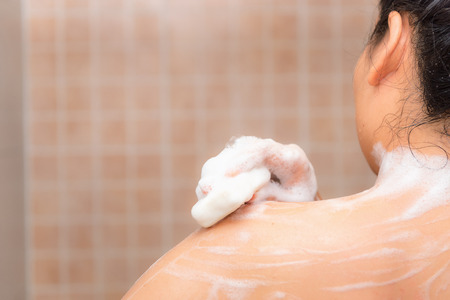 Portrait of beautiful woman taking shower with bath sponge and soap.の写真素材