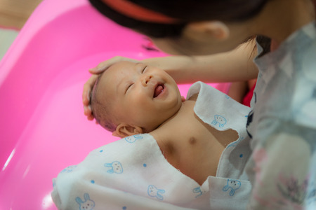 Little baby having fun while mother bathing for her in plastic bath.の写真素材