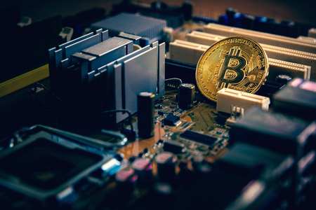 Golden bitcoin cryptocurrency on computer electronic circuit board.の写真素材
