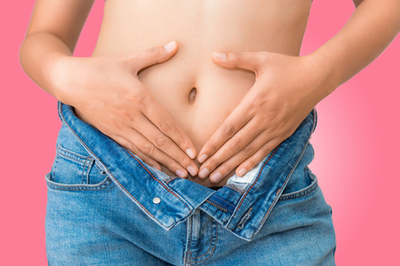 Close up portrait of woman's hands holding on belly. Healthcare and diet concept.の写真素材