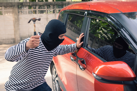Car thief breaking a car's windows to steal a woman bag.の写真素材