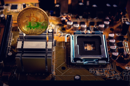 Golden bitcoin cryptocurrency on computer electronic circuit board.