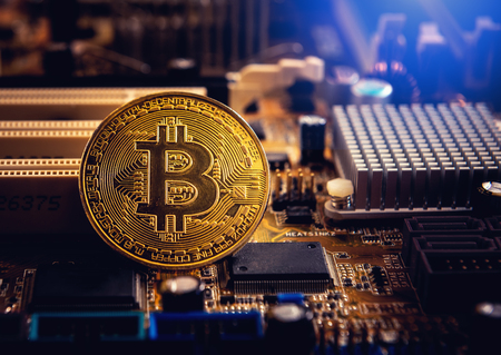 Golden bitcoin cryptocurrency on computer electronic circuit board.の写真素材