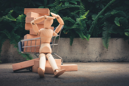Shopping concept, Mini wooden model is resting in front of trolley shopping.の写真素材