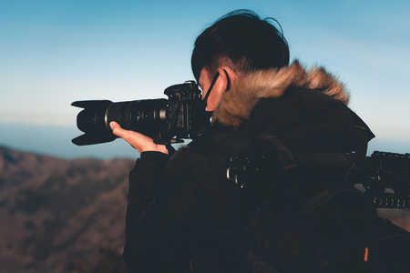 Silhouette of photographer is shooting picture on top of mountain at sunrise scene.