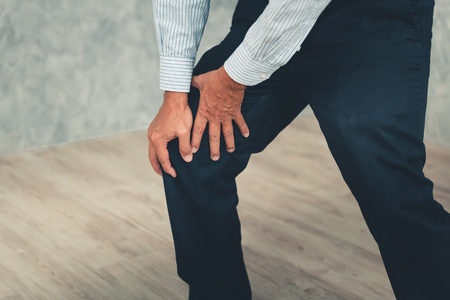 Close up portrait of elderly man suffering in his knee while he standing up.の写真素材