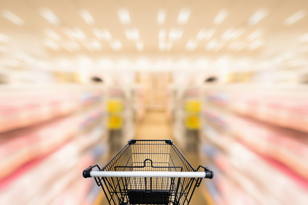 Shopping trolley in department store with consumer goods product on shelf background., Abstract motion blurred concept.の写真素材