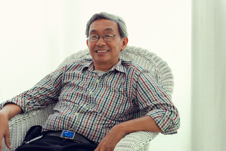 Portrait of senior man is sitting in an armchair and relaxing at home.の写真素材
