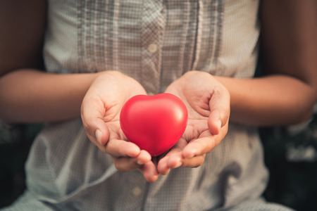 Woman hands holding red heart to giving someone.の写真素材