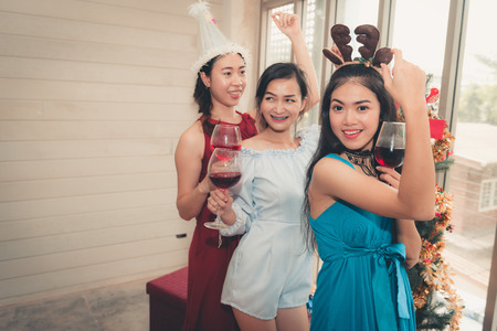 Party concept, Portrait of young woman having fun while holding a glass of wine in Christmas party.の写真素材