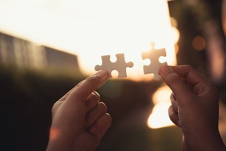 Closeup of woman hands joining pieces of jigsaw puzzle together.,Business solutions, success mission concept.の写真素材