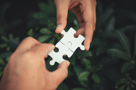 Closeup of man and woman hands connecting jigsaw puzzle together, Business solutions, success mission concept.の写真素材