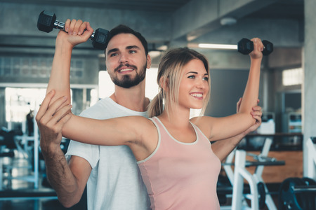 Portrait of sexy woman in fitness gym training with dumbbell equipment., Couple caucasian are working out and training together in gym club., Sport and healthy concept.の写真素材