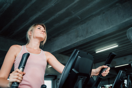 Portrait of sporty woman exercising elliptical in fitness gym., Group of pretty women in sportswear working out cardio training at gym.,Wellness program and sport healthy concept.の写真素材