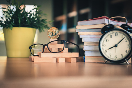 Golden bitcoin cryptocurrency beside alarm clock with dominoes falling on the table., Stock exchange and currency investment risk.,Business financial and banking bitcoin concept.の写真素材