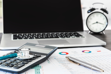 Stethoscope and calculator on doctor office table and equipment tools., Table workspace desktop for examining patient health., Business healthcare insurance and medicine concept.の写真素材