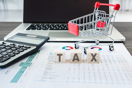 Business E-Commerce Online and Financial Tax Accounting Concept., Calculator and Mini Cart on Data Fact Sheet in Front of Personal Computer Laptop Background., Customer shopping and E-Payment Concept.の写真素材