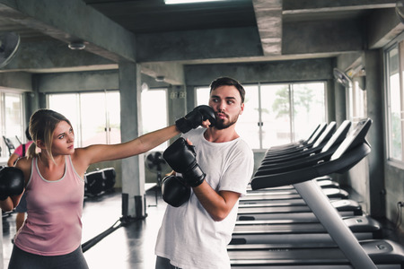 Two Sporty Couple are Training Boxing in Fitness Club, Young Woman is Knock-Out Punching to Her Boyfriend, Sport and Healthy Concept.の写真素材