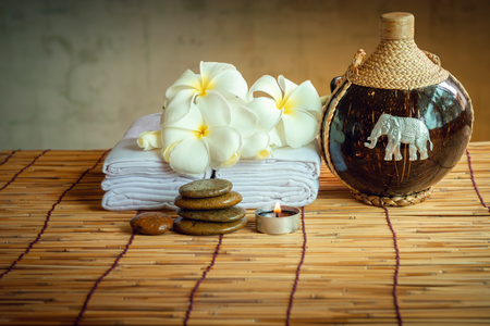 Spa Oil Massaging Treatment and Skincare Concept., Component of Therapy Massage With Plumeria or Frangipani Flowers, Towel, Stones, Aroma Candle and Oil on The Desk.の写真素材