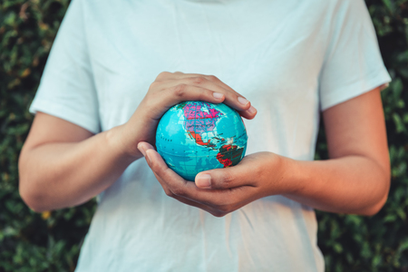 Save The Earth and Care Environment Concept, Close-up Portrait of Woman is Holding Mockup Global in Her Hands on Tree Leave Background. Save The Planet and Traveling Conceptual.の写真素材