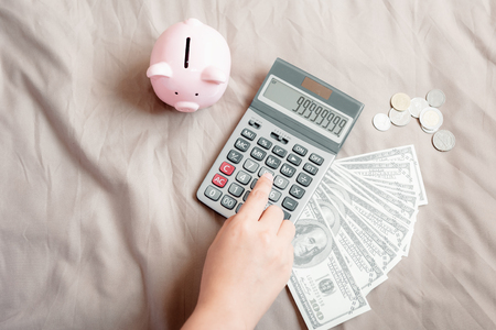 Close-Up of Woman Hand is Using Calculator for Calculated Accounting Money Saving or Expense Claim on Her Bedroom, Business Banking and Financial Concept.の写真素材