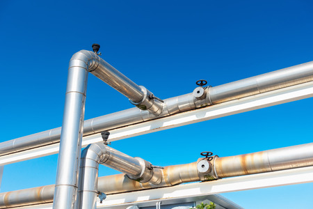 Cooling Chiller or Steam Pipeline and Insulation of Manufacturing in Oil and Gas Industrial, Petrochemical Distribution Pipe at Refinery Plant. Overhead Steel Pipe Support on Blue Sky Background.の写真素材