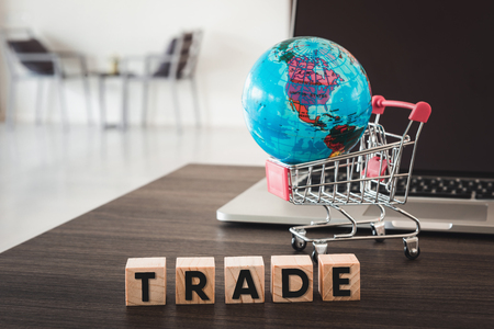 Business Trading and E-Commerce Online and Financial Concept., Computer, Global Model, Shopping Cart and Wooden Cube With Text on Table Desk.の写真素材