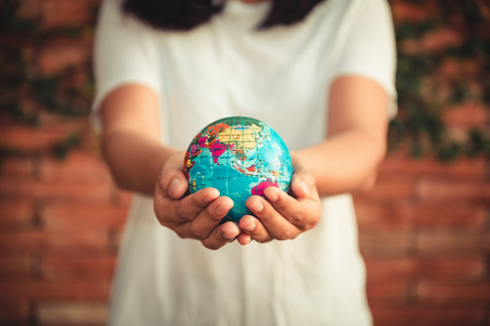 Save The Earth and Care Environment Concept, Close-up Portrait of Woman is Holding Mockup Global in Her Hands on Tree Leave Background. Save The Planet and Traveling Conceptual.の写真素材