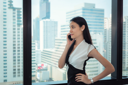 Portrait of Business Woman is Talking on Mobile Phone in Office Workplace, Attractive Beautiful Businesswoman is Talking on Cellphone While Working at Her Workspace.,Communication Concept.の写真素材