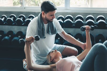 Portrait of Couple Love in Fitness Training With Dumbbell Equipment, Young Couple Caucasian are Working Out and Training Together in Gym Club, Sport and Healthy Concept.の写真素材