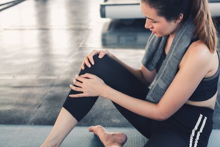 Close Up of Pretty Woman Having Injury During Exercise in Gym While Yoga Practice, Accident and Sport Fitness Concept.の写真素材